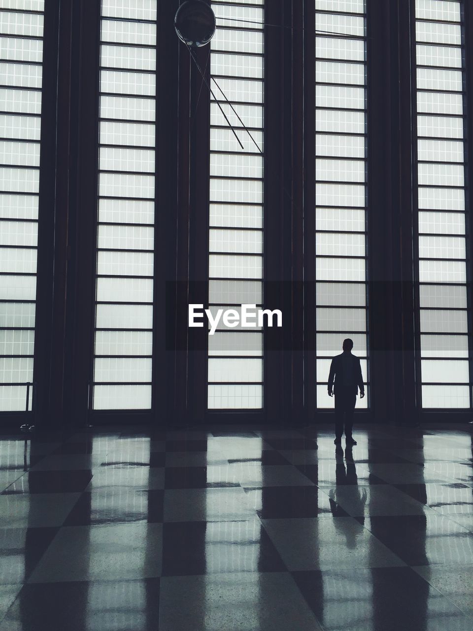 Silhouette of man standing by window in modern building