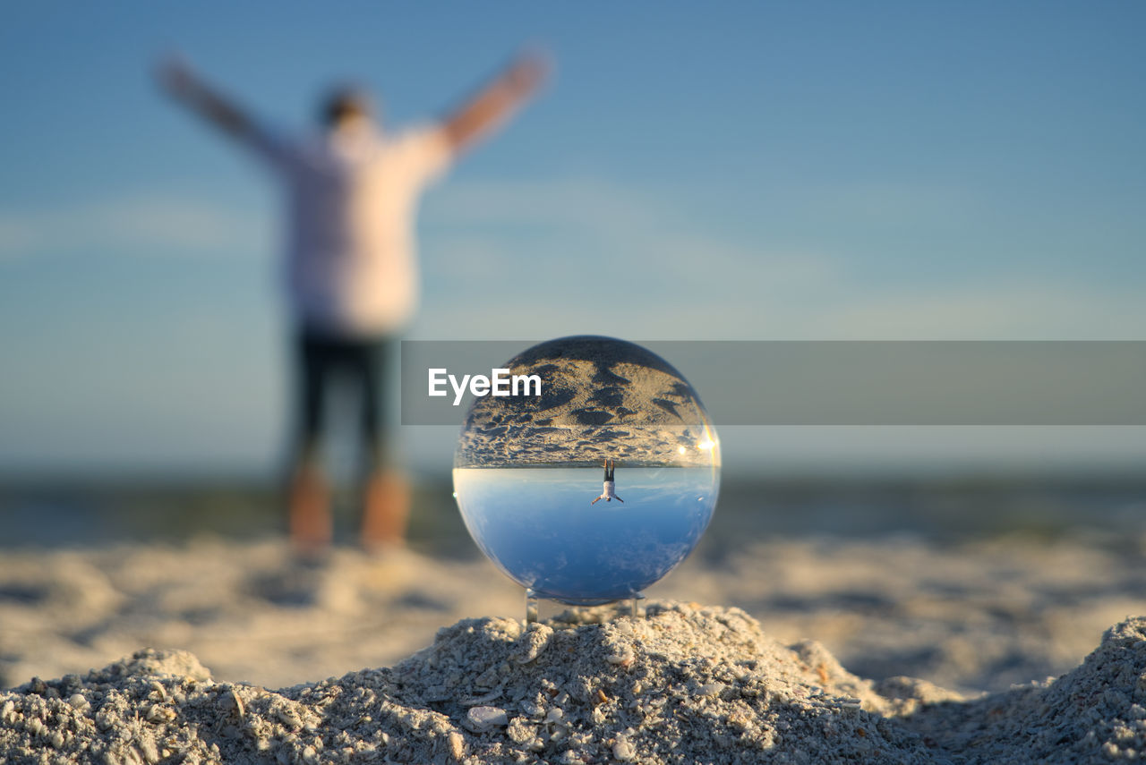 Man enjoys freedom on the beach at sanibel island, taken through a glass ball