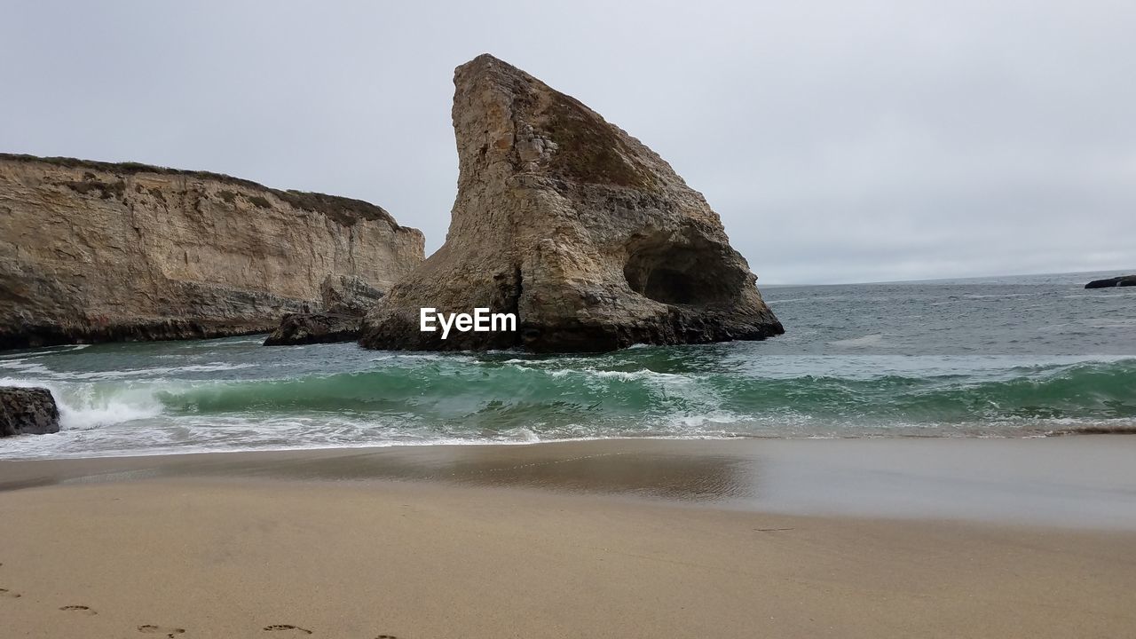 Rock formation on beach against sky