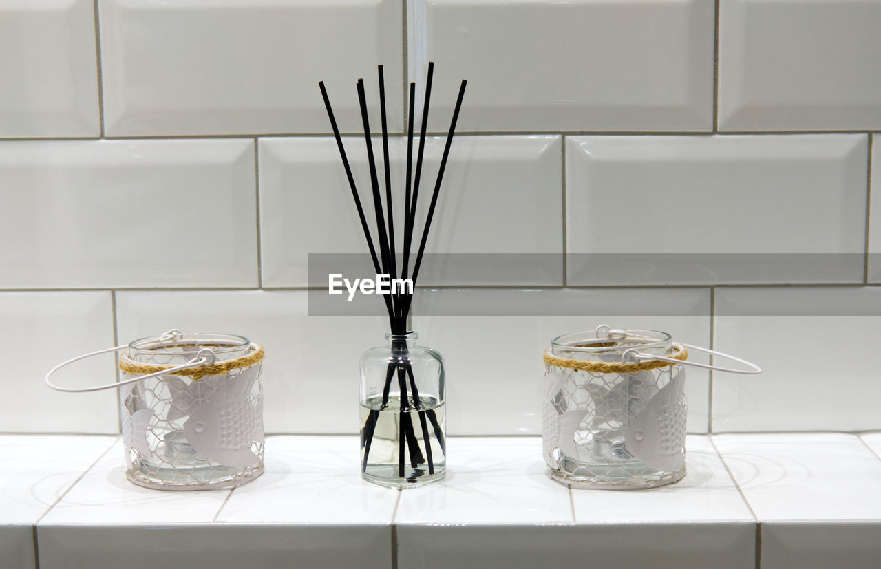 Incense holder and candle holders on white shelf in bathroom