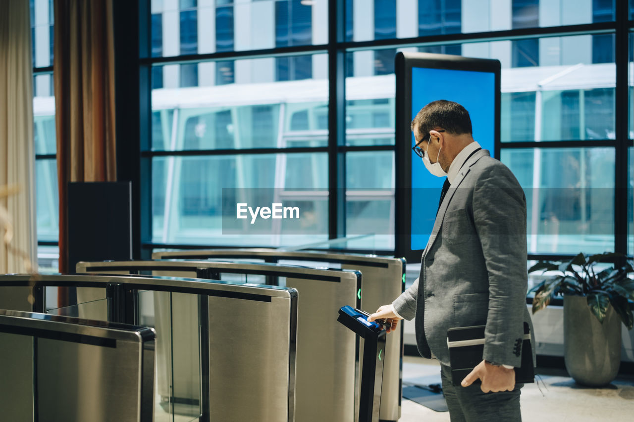 Businessman scanning smart phone to enter subway station during covid-19