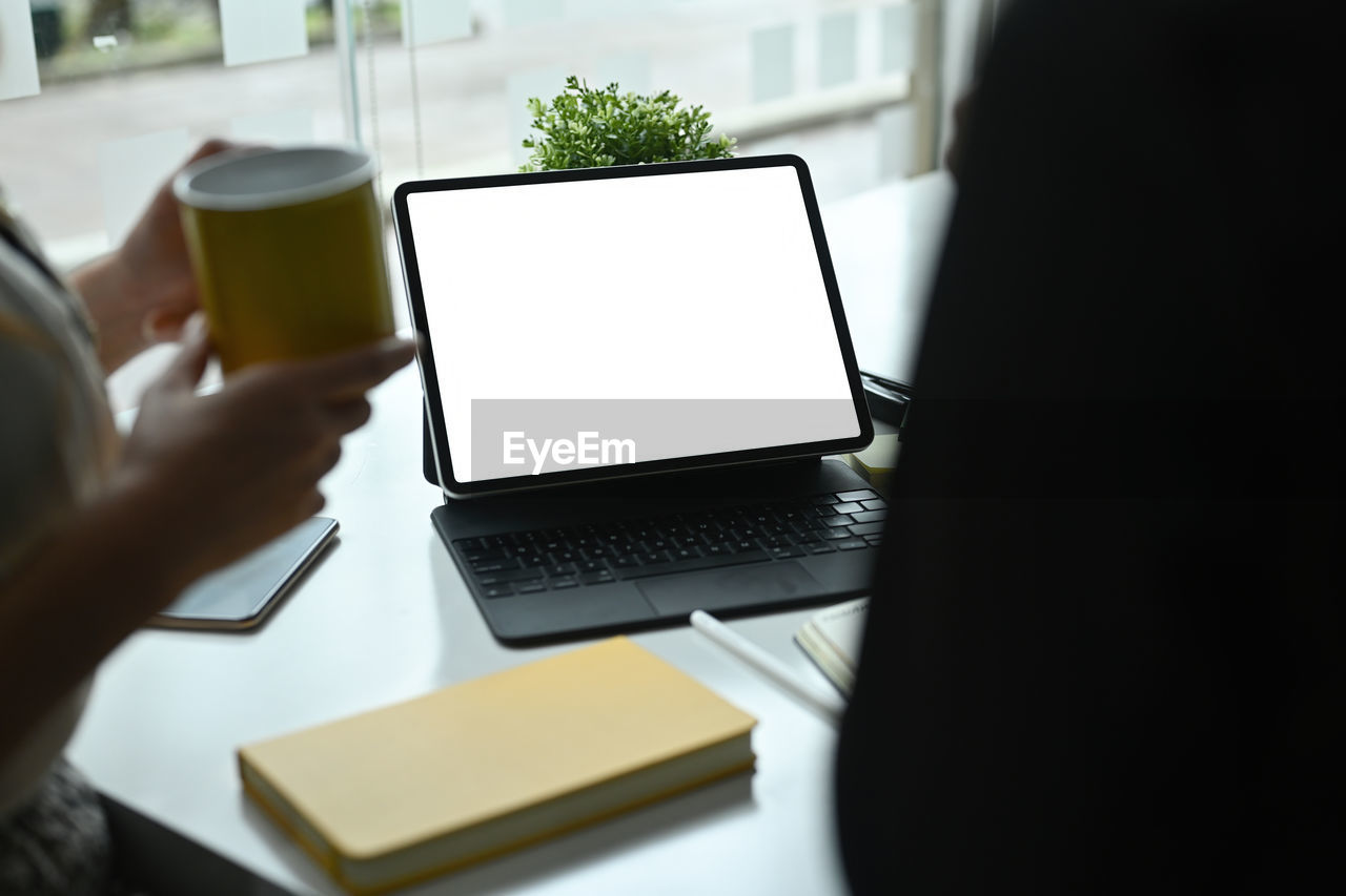 computer, technology, wireless technology, communication, adult, table, business, laptop, indoors, furniture, desk, working, writing, using laptop, one person, office, houseplant, hand, computer equipment, internet, women, occupation, computer monitor, selective focus, plant, business finance and industry, portability, computer network, using computer, young adult, sitting, food and drink, men, day, high angle view, convenience, planning, businessman, place of work