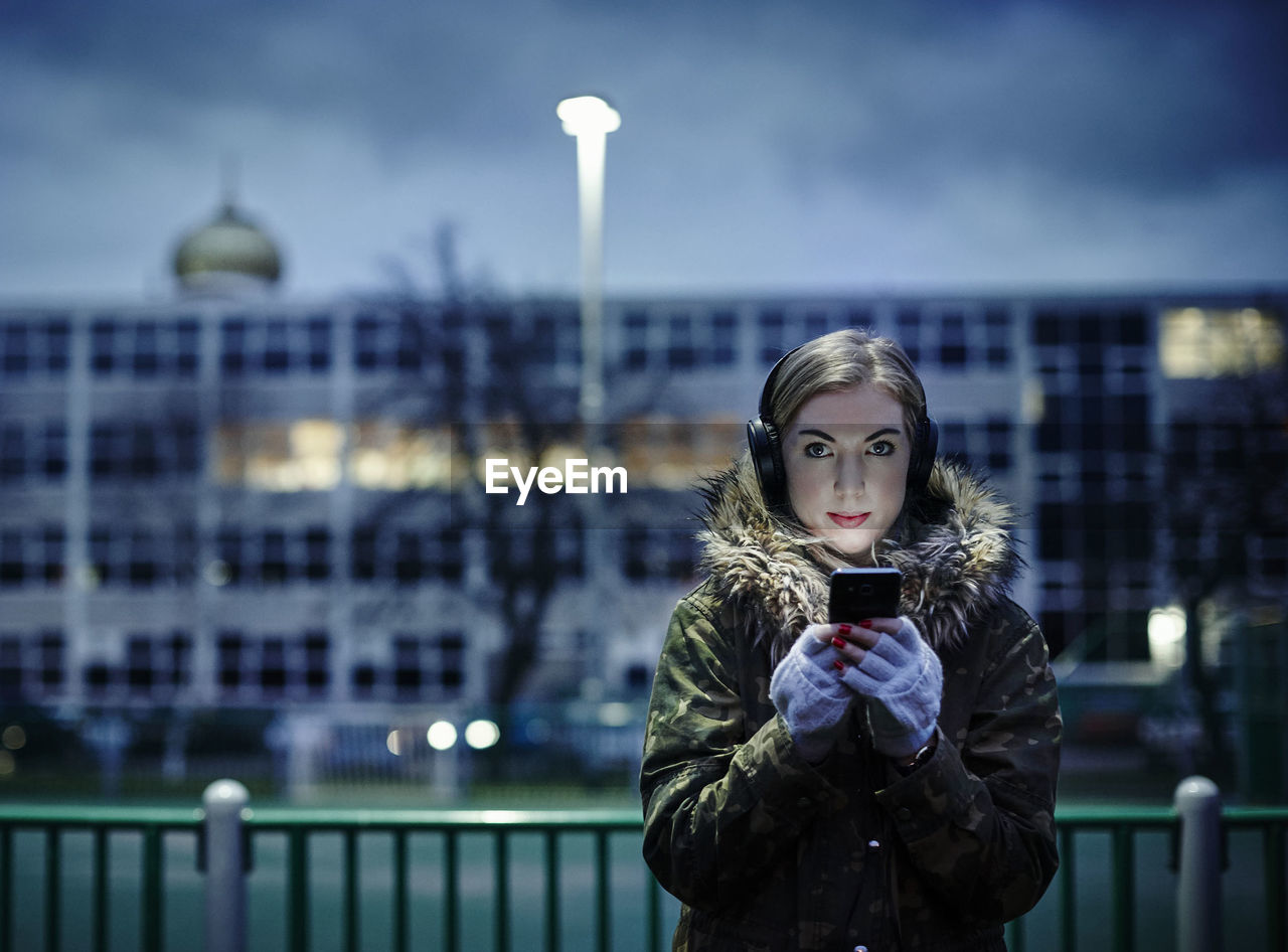 Portrait of young woman using mobile phone in city