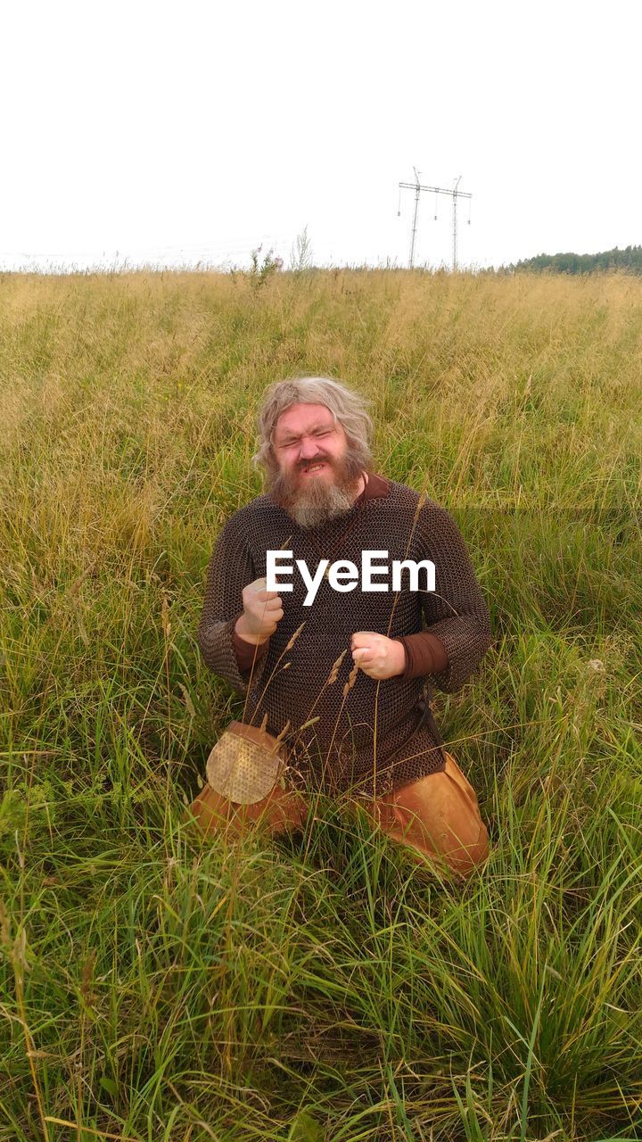 PORTRAIT OF MAN ON GRASSY FIELD