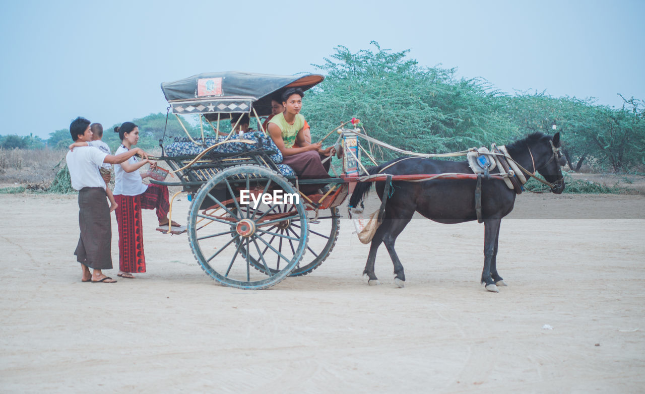 PEOPLE RIDING MOTORCYCLE ON CART AT FARM