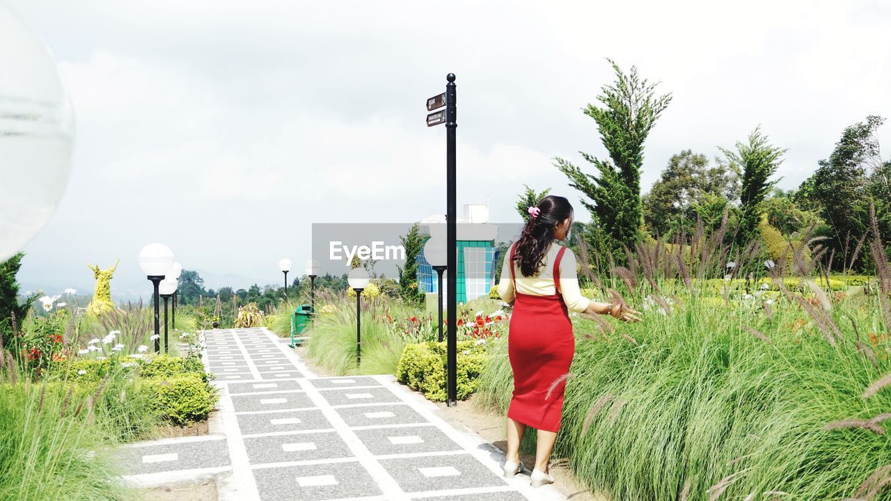 WOMAN STANDING ON ROAD AGAINST SKY