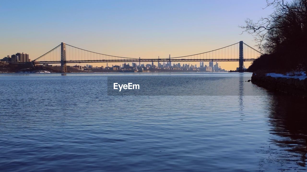 View of suspension bridge over river with sunset