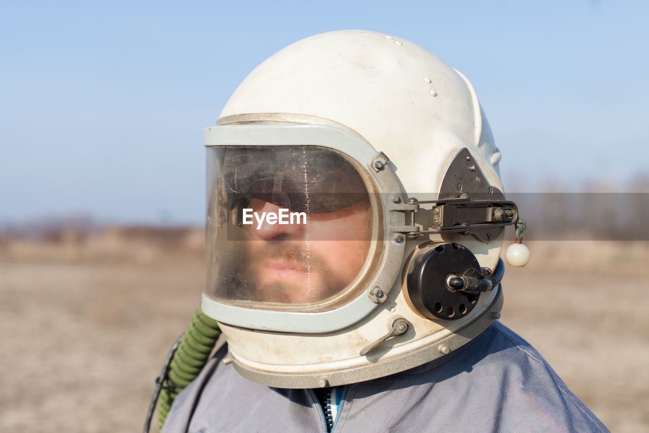 Close-up of man wearing helmet on field against sky