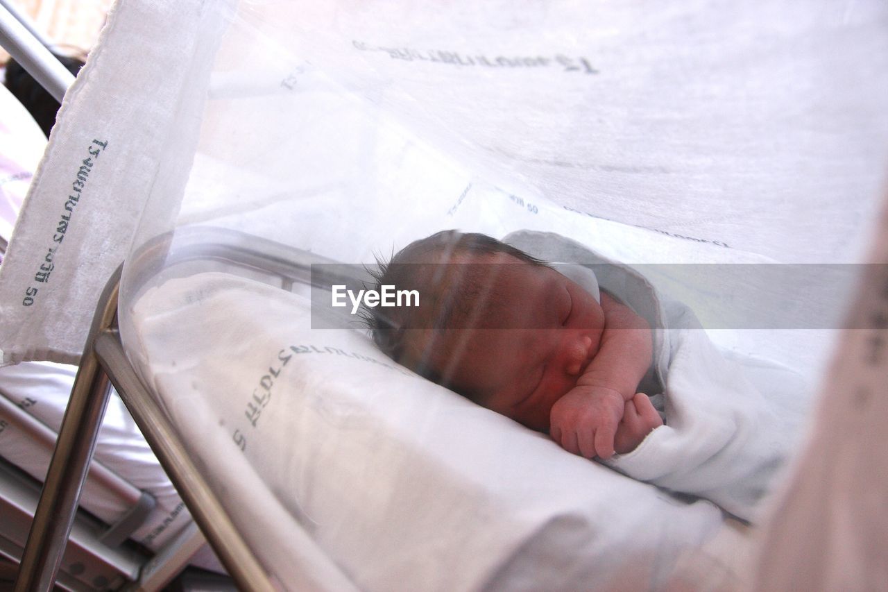 Close-up of newborn baby sleeping bed in hospital