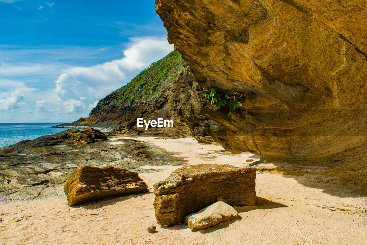 Rock formation on beach against sky