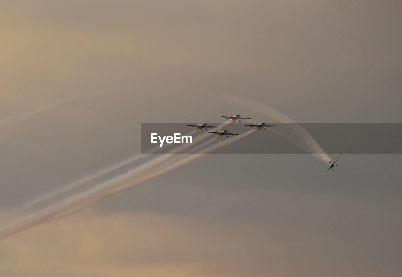 Low angle view of airplanes flying against sky during sunset