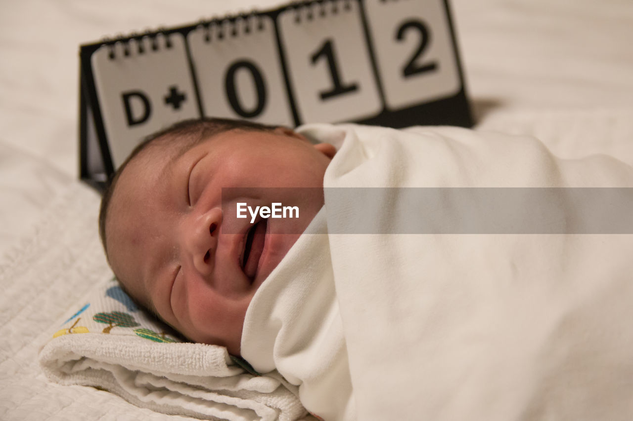 Close-up of baby girl lying on bed