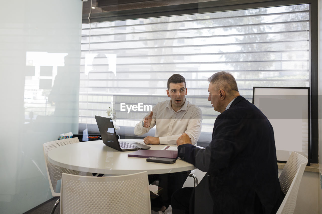 Businessman with colleague discussing at desk in office