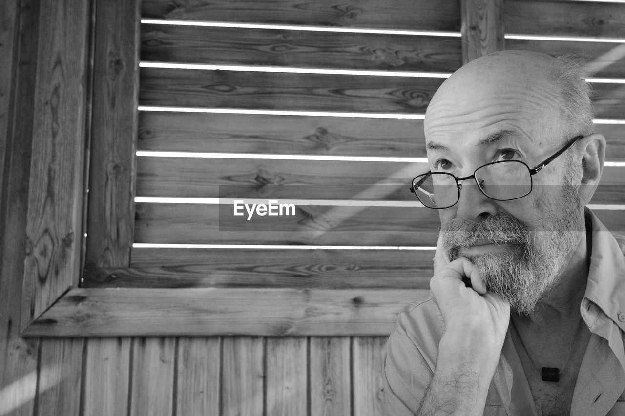 wood, one person, adult, glasses, men, black and white, white, eyeglasses, portrait, senior adult, lifestyles, monochrome, headshot, monochrome photography, facial hair, beard, leisure activity, front view, mature adult, looking, black, casual clothing, relaxation, day, architecture, indoors, contemplation, looking away, person