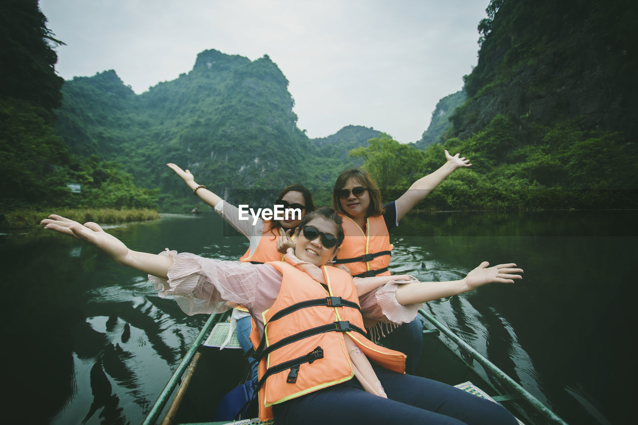 Portrait of smiling women sitting in boat at river 