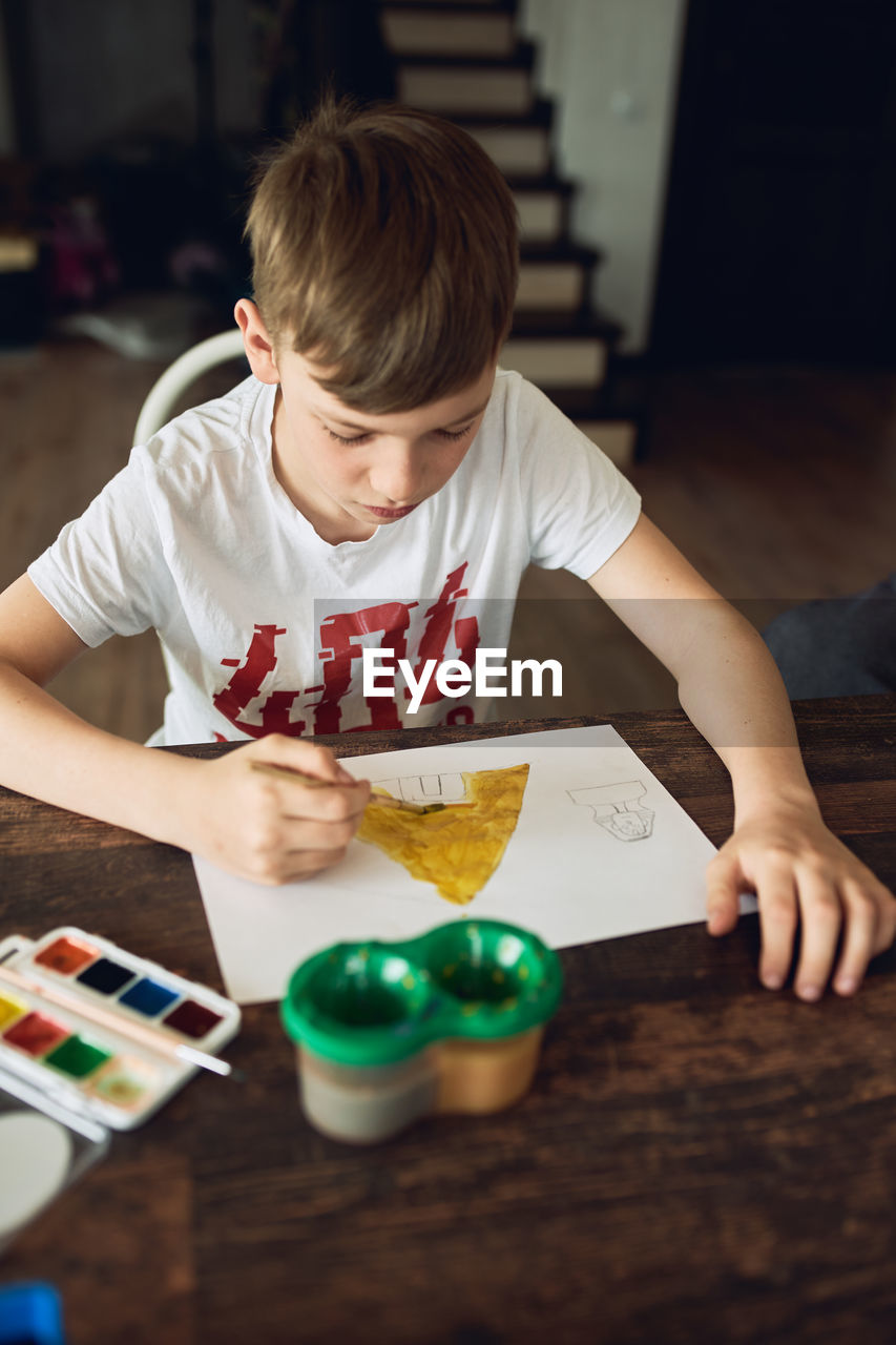 Rear view of boy looking at table at home