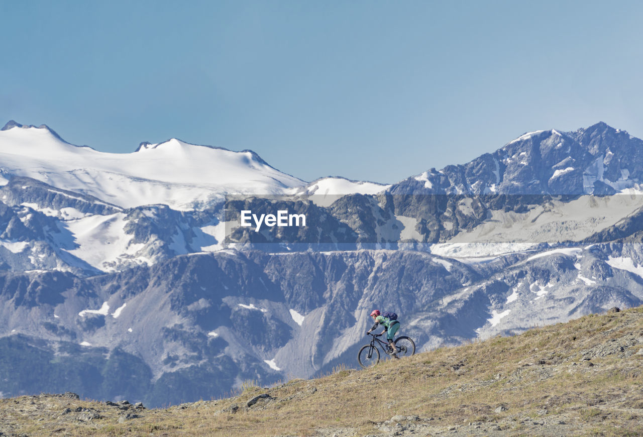 Man riding bicycle on mountain against sky