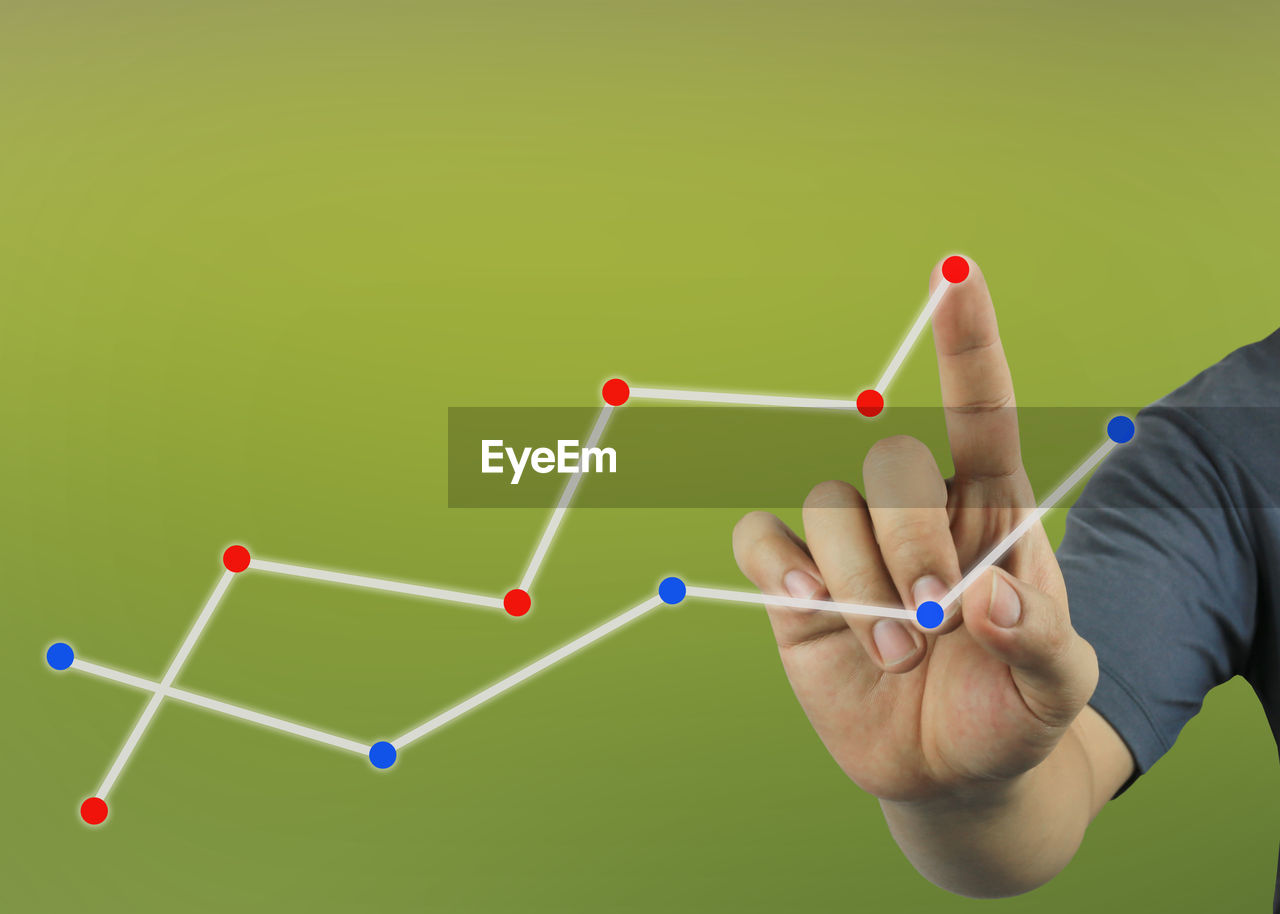 Digital composite image of hand touching line graph on invisible screen