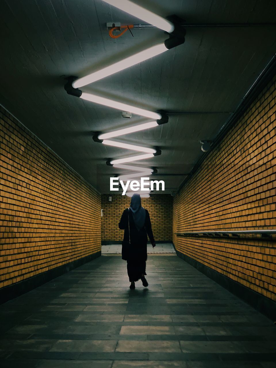 Rear view of woman walking in illuminated subway