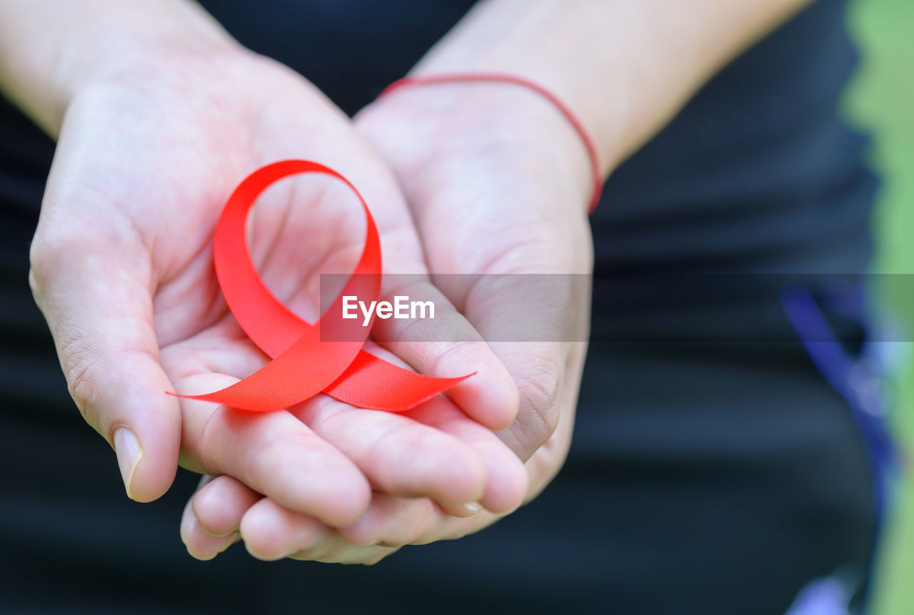 Midsection of woman with aids awareness ribbon on hand