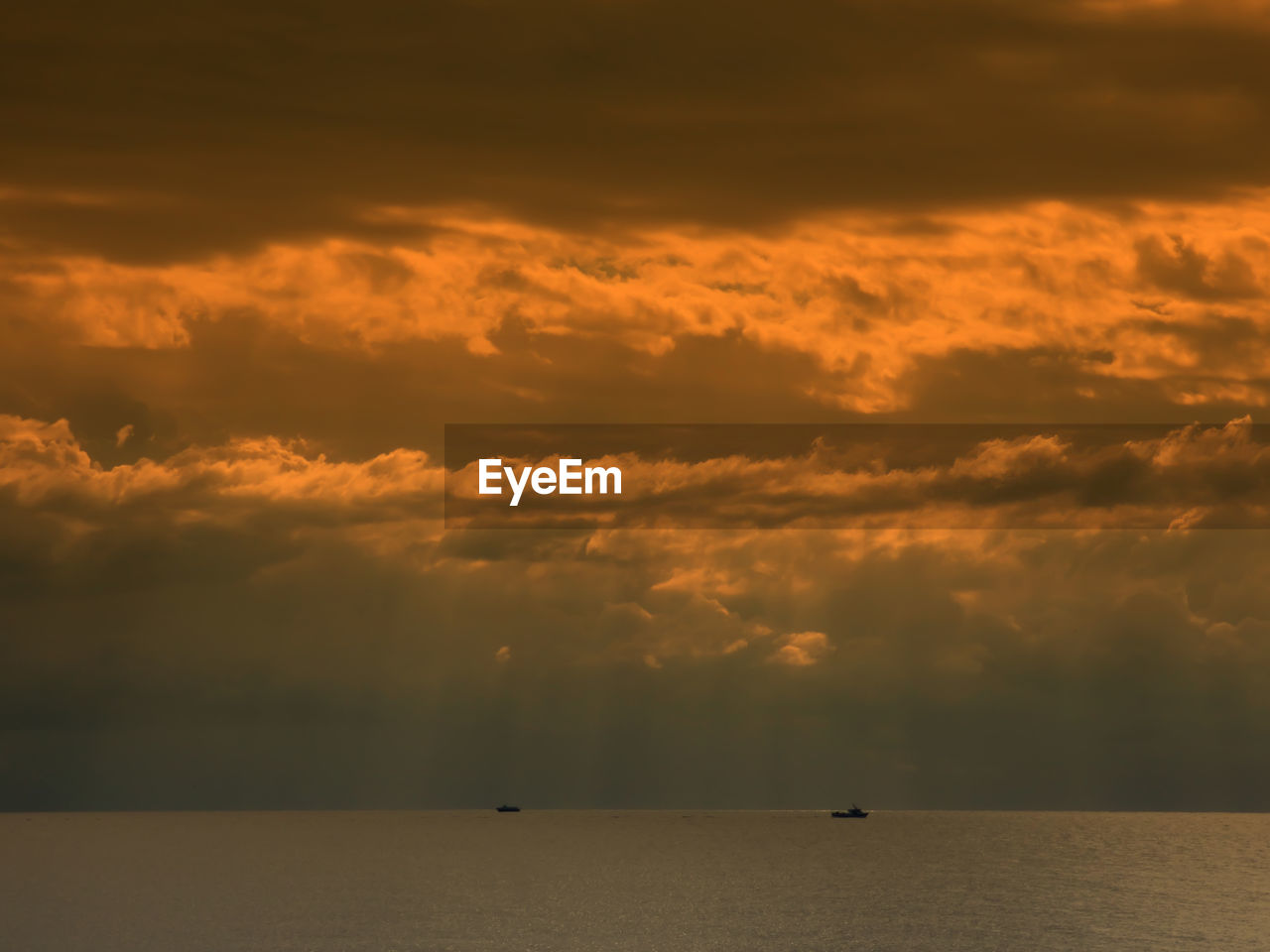 Scenic view of sea against cloudy sky during sunset