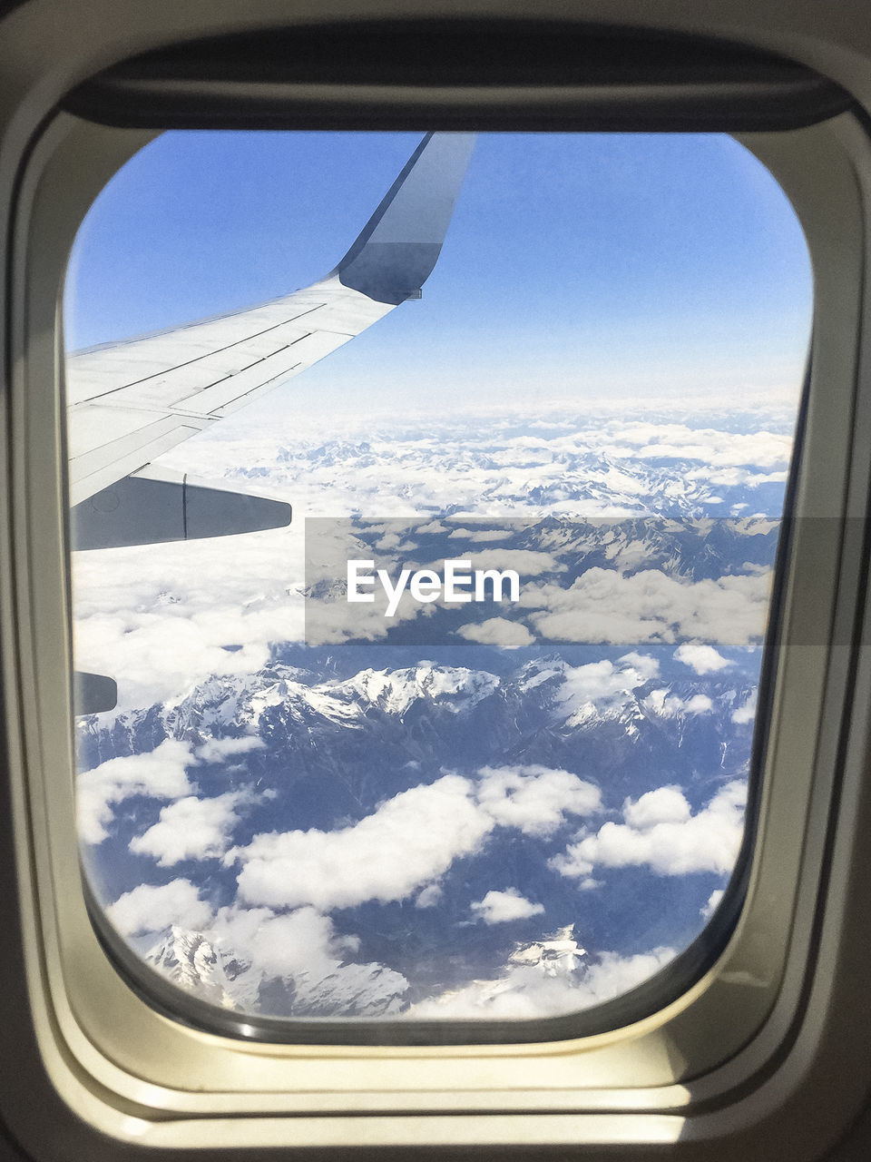 CROPPED IMAGE OF AIRPLANE WING OVER MOUNTAIN LANDSCAPE