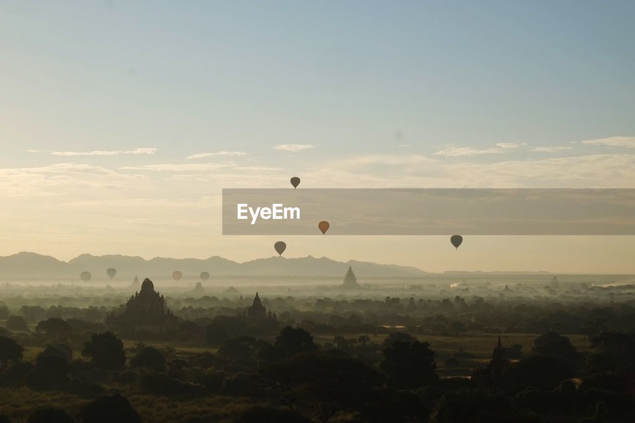 Hot air balloons flying over landscape against sky