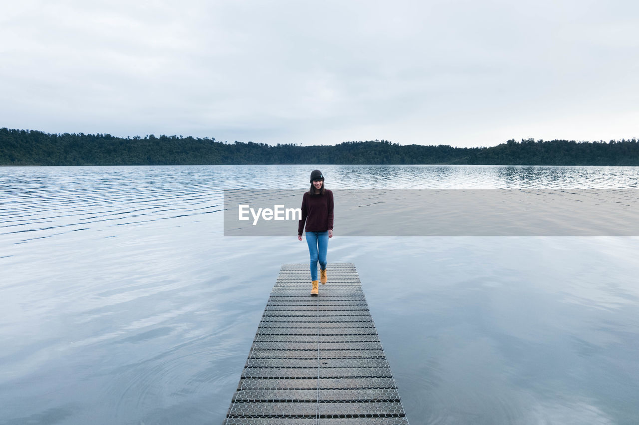 Young woman walking on jetty over lake