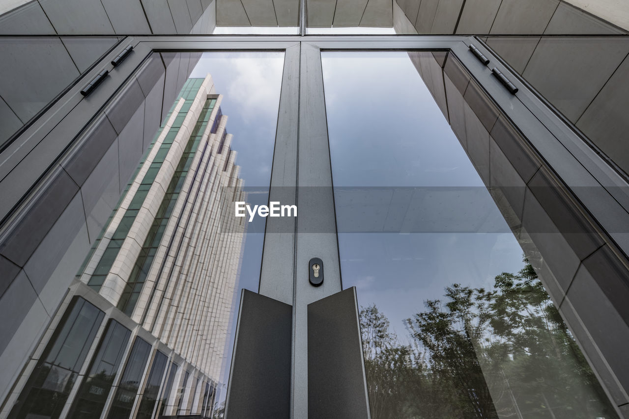 LOW ANGLE VIEW OF MODERN GLASS BUILDING AGAINST SKY