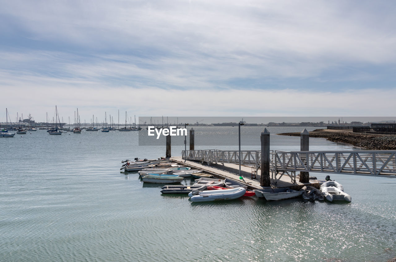 SAILBOATS MOORED AT SEA AGAINST SKY