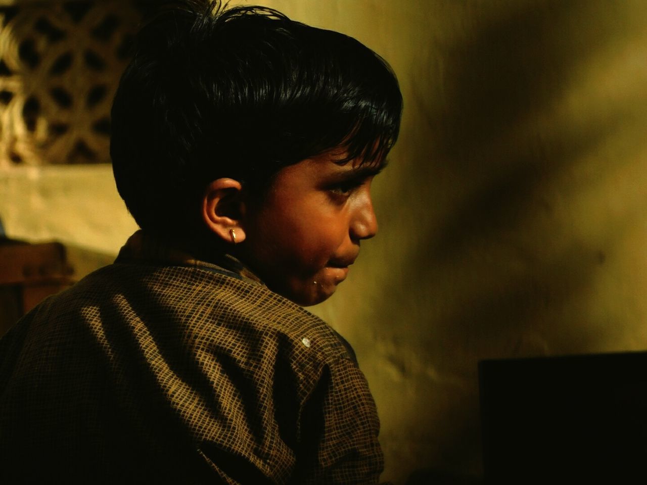 Rear view of thoughtful boy looking away against wall