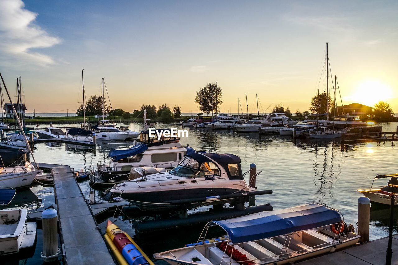 BOATS MOORED AT HARBOR DURING SUNSET