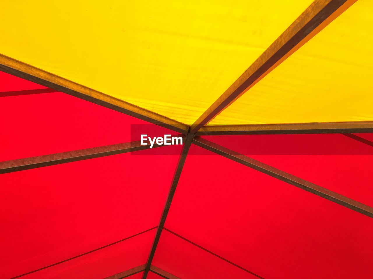 LOW ANGLE VIEW OF MULTI COLORED UMBRELLA AGAINST RED BACKGROUND