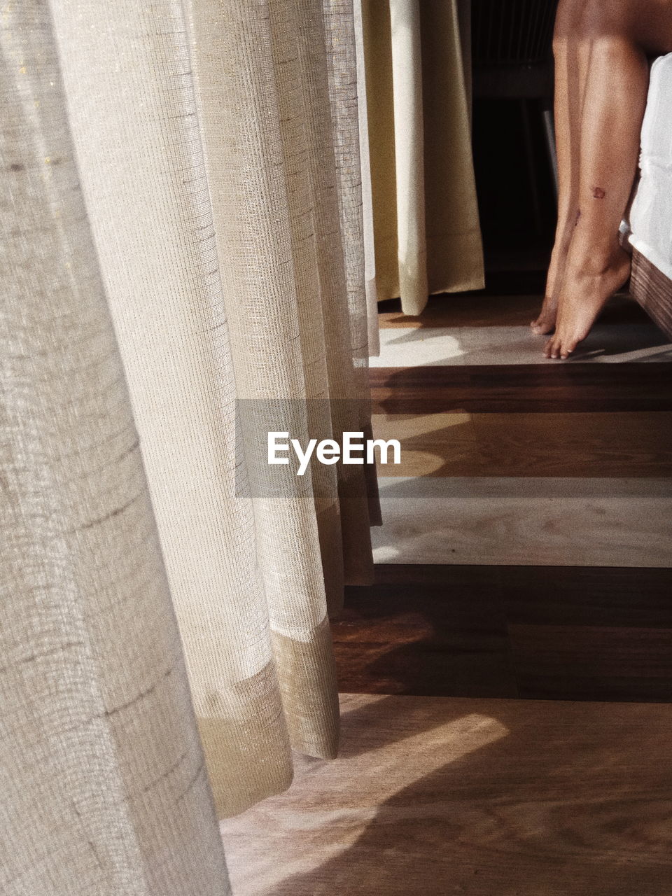 Low section of woman by curtain in bedroom