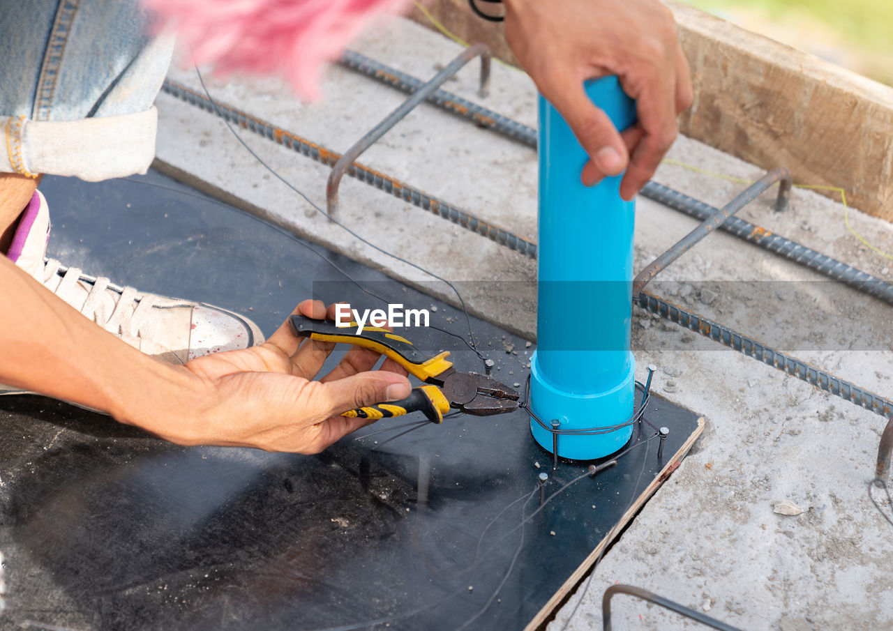 Worker use plies wire bundle tap water in formwork before pour concrete beam.