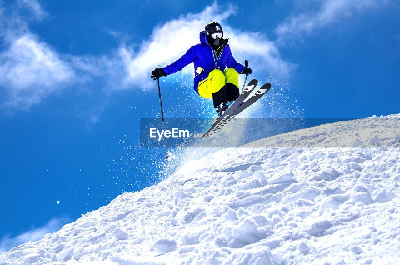 Low angle view of person skiing over snow covered field against sky