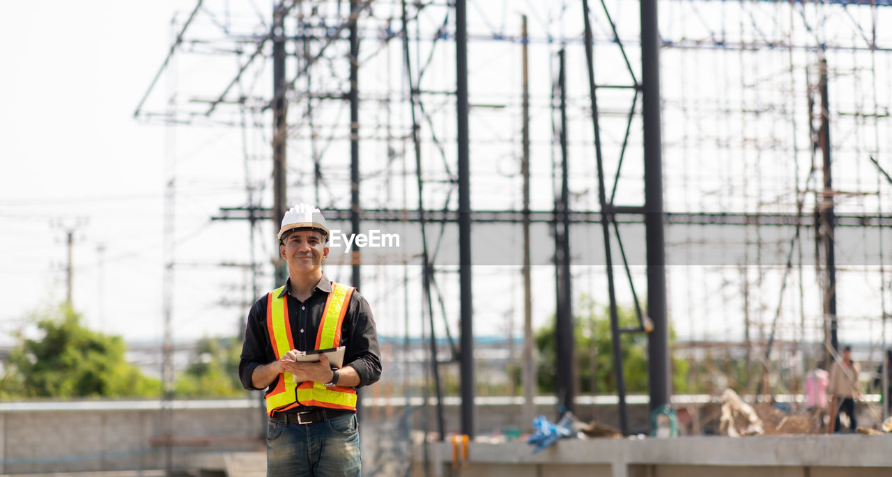 PORTRAIT OF MAN WORKING WITH ARMS OUTSTRETCHED STANDING ON WOOD