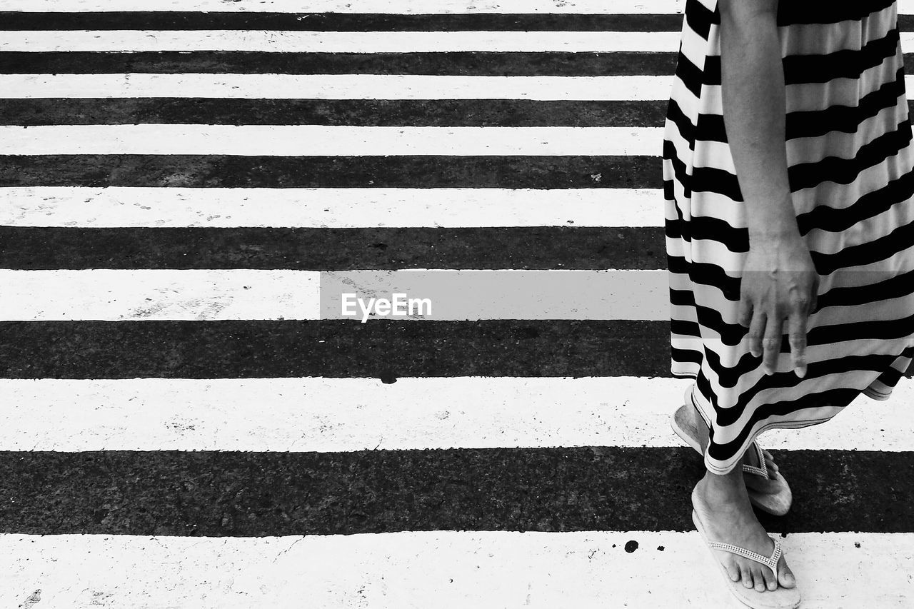 Low section of woman standing on zebra crossing