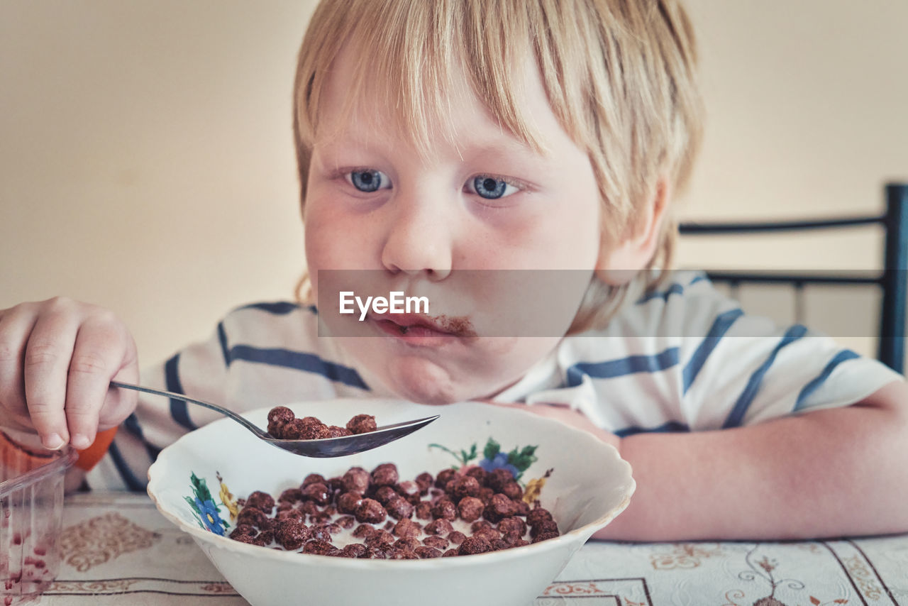 close-up portrait of cute boy eating food at home