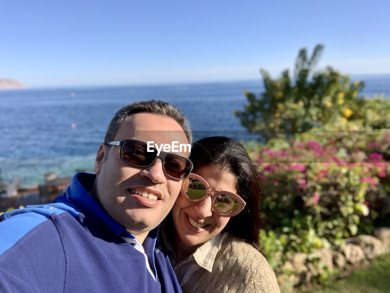 two people, adult, sunglasses, portrait, glasses, togetherness, smiling, happiness, vacation, men, emotion, nature, fashion, women, love, sea, sky, positive emotion, headshot, water, looking at camera, bonding, leisure activity, sunlight, day, female, sunny, blue, mature adult, outdoors, beach, casual clothing, lifestyles, person, holiday, land, trip, young adult, plant, cheerful, human face, clear sky, focus on foreground, affectionate, enjoyment, romance, embracing, front view, summer, friendship, travel destinations, beauty in nature, travel, relaxation, copy space