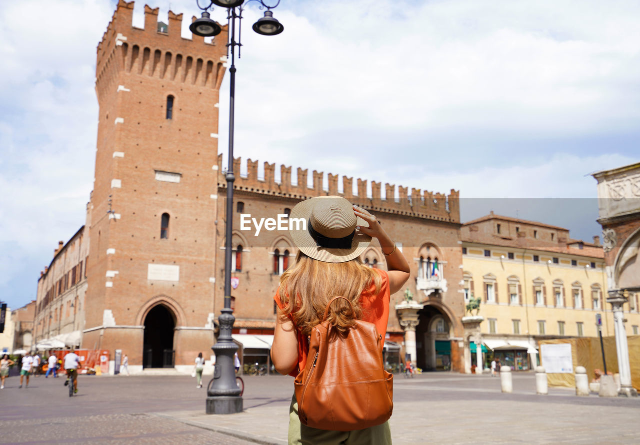 Cultural tourism in italy. rear view of female backpacker visiting medieval town of ferrara, italy
