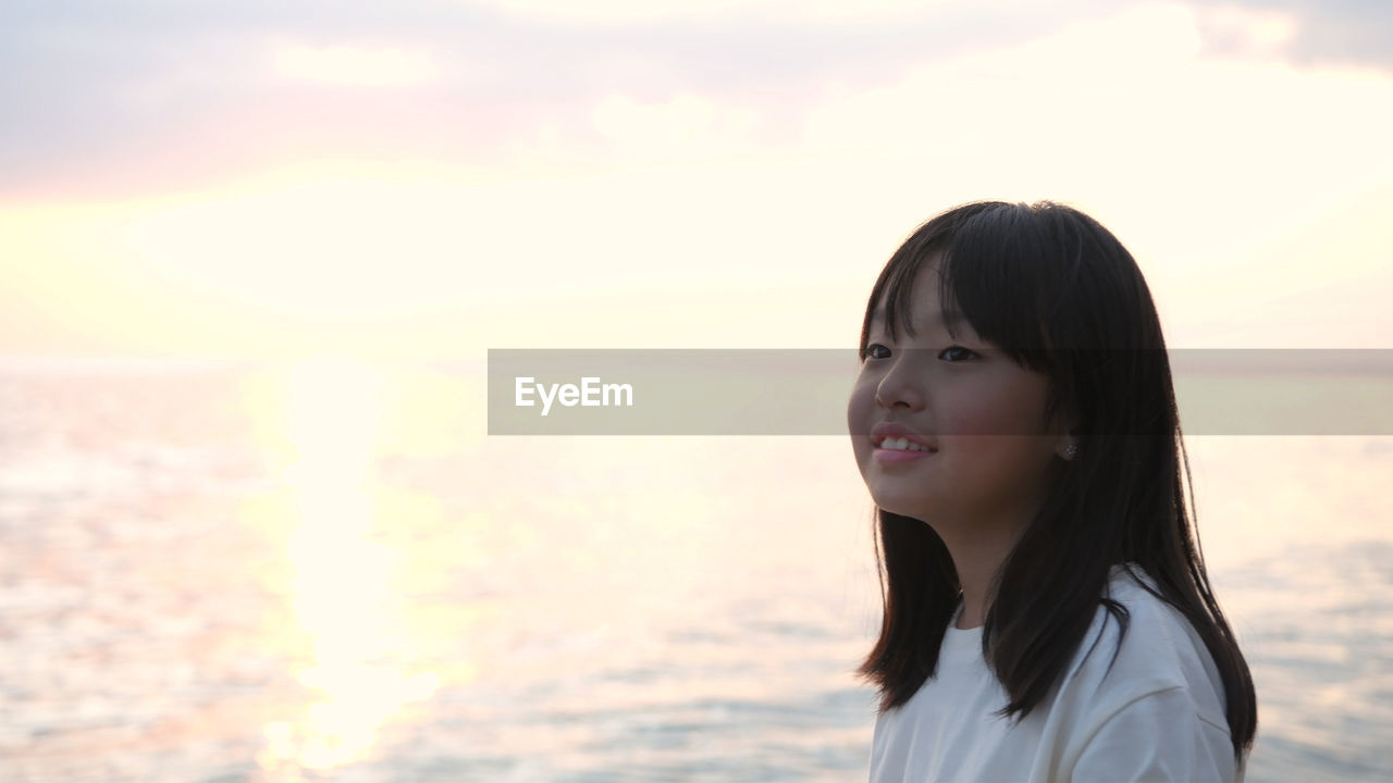 Portrait of woman standing at beach during sunset