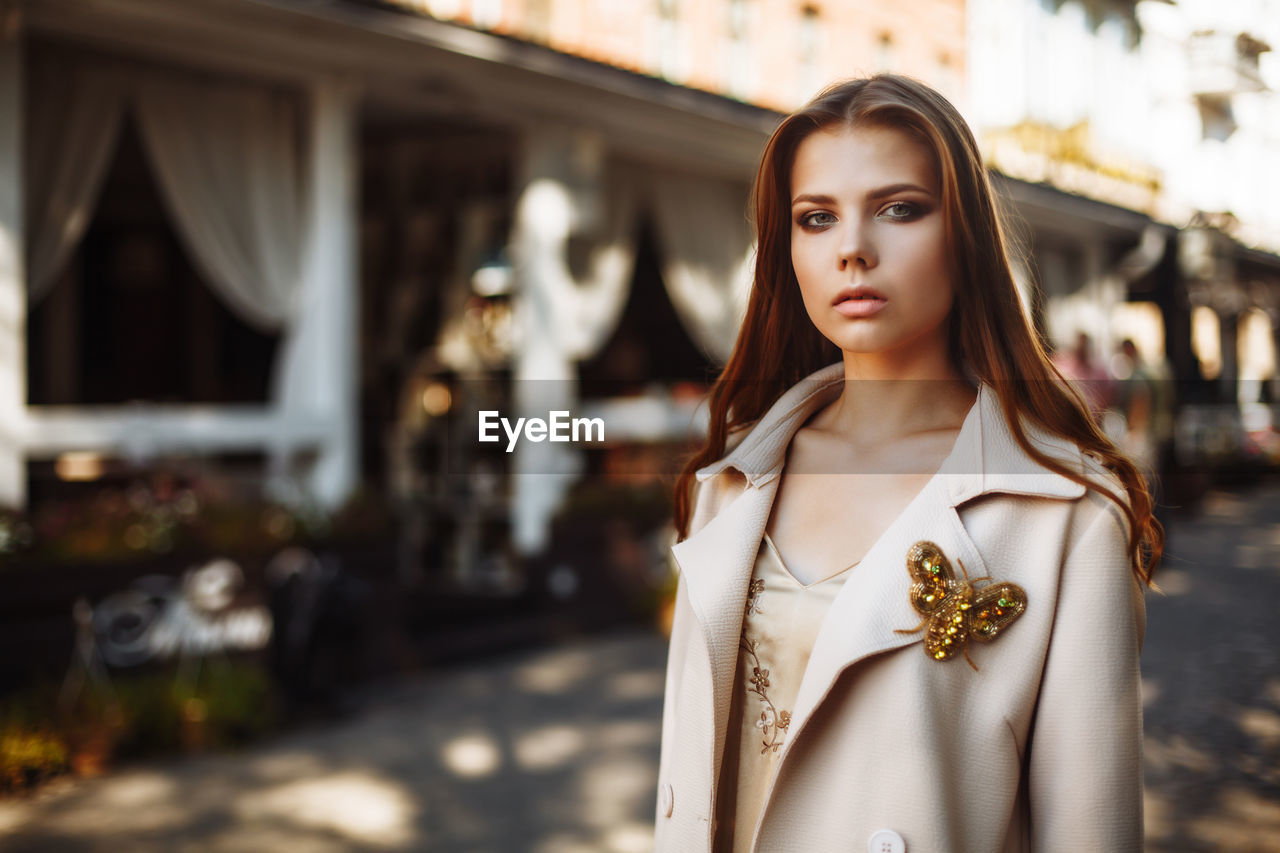 Fashionable young woman wearing overcoat in city