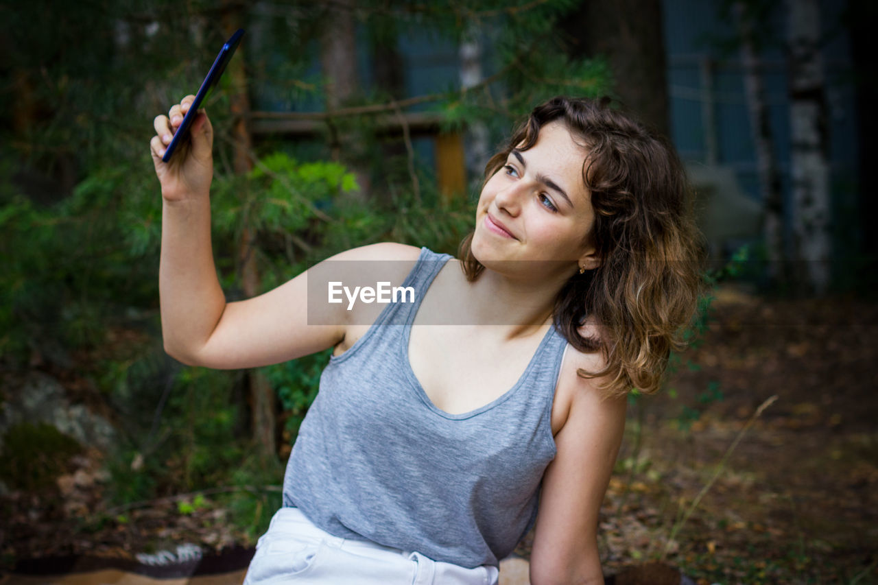 Beautiful teenager girl taking a selfie at the forest. using technology