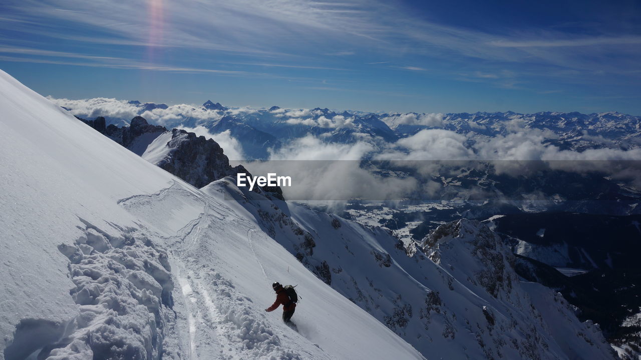 Person on snowcapped mountain against sky