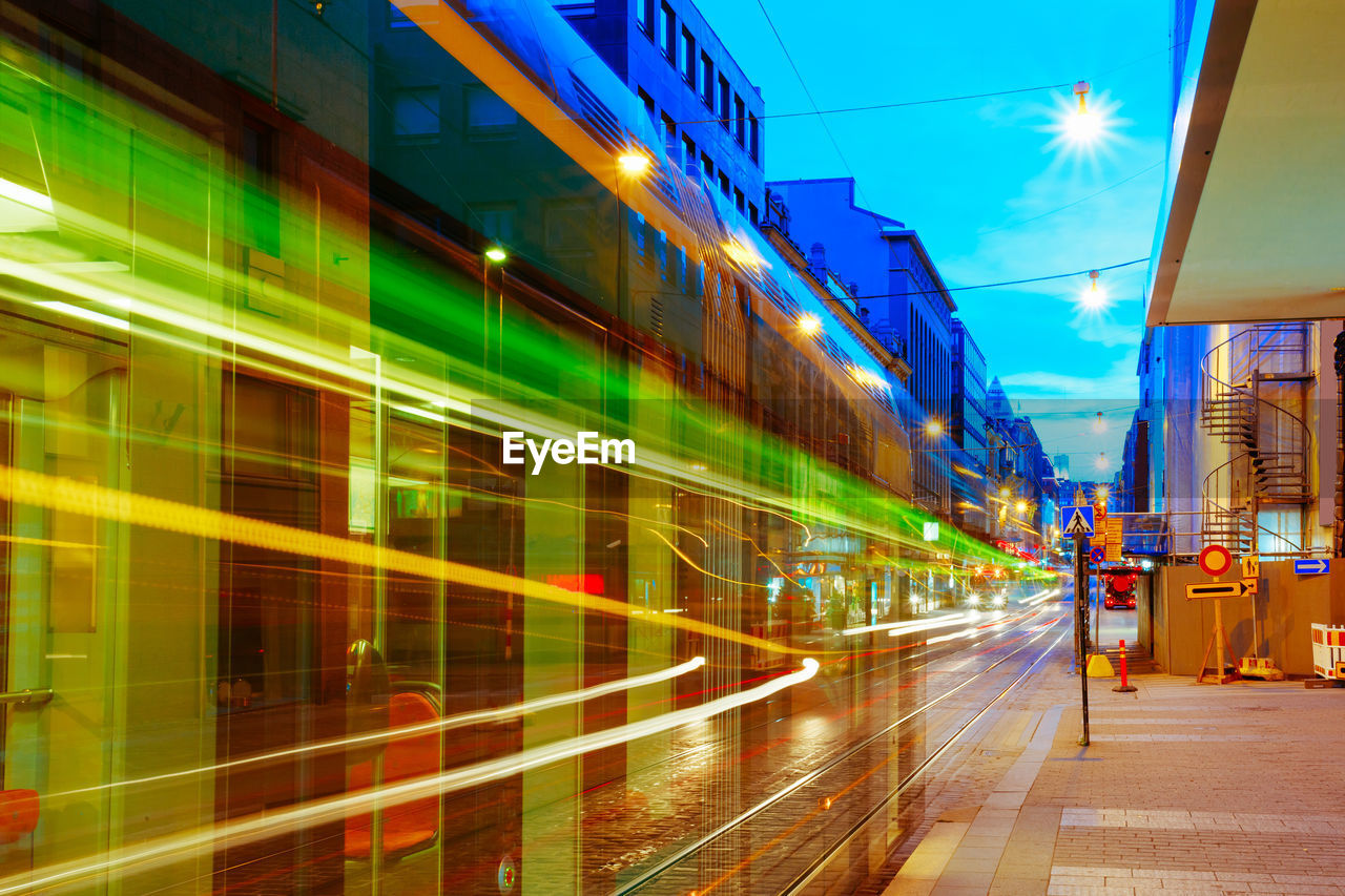 Blurred motion of cable car by buildings in illuminated city during sunset