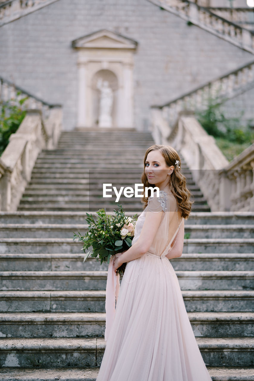 portrait of young woman standing on staircase