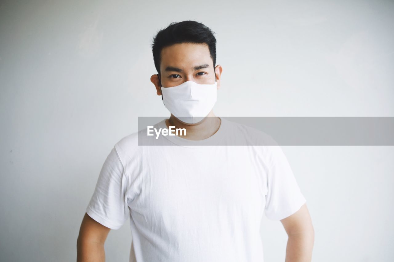 Portrait of man wearing mask standing against white background