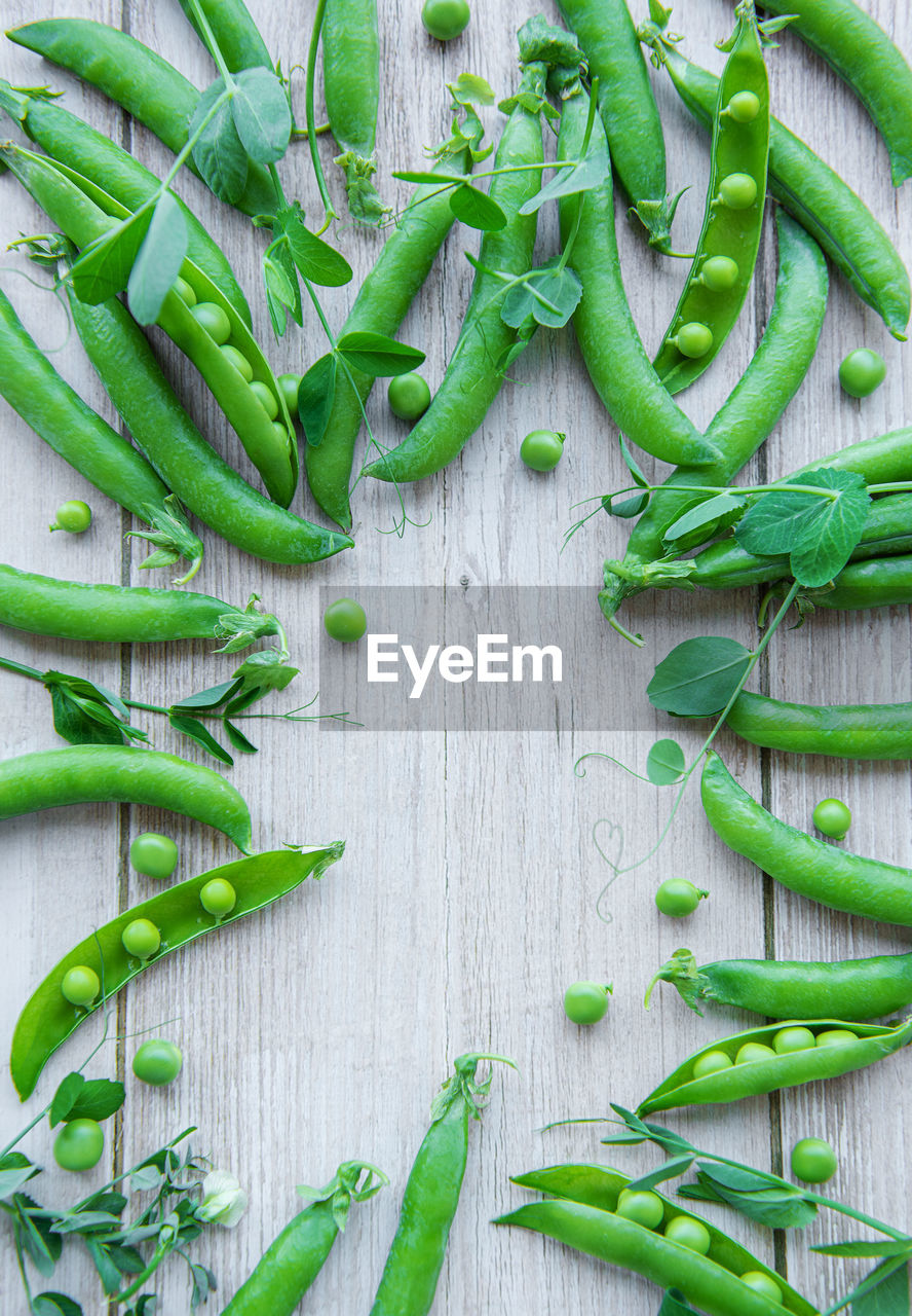 Green peas with leaves on a wooden background