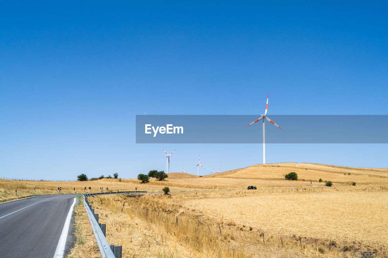 WIND TURBINES ON FIELD AGAINST CLEAR SKY